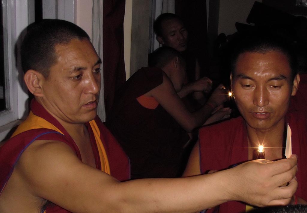 two monks look at a bright point of light